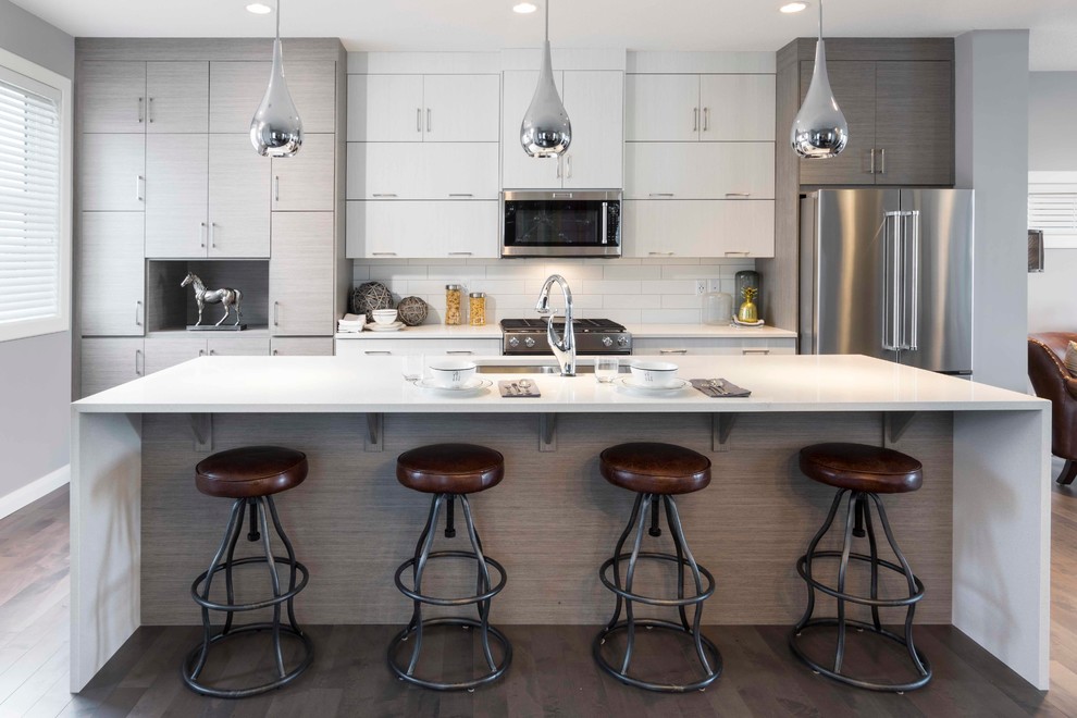 Inspiration for a contemporary kitchen in Calgary with an undermount sink, flat-panel cabinets, white cabinets, white splashback, subway tile splashback, stainless steel appliances and with island.