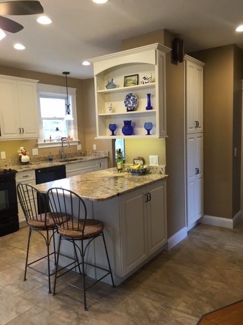 Mid-sized transitional galley porcelain tile eat-in kitchen photo in Boston with an undermount sink, raised-panel cabinets, white cabinets, granite countertops, black appliances and an island