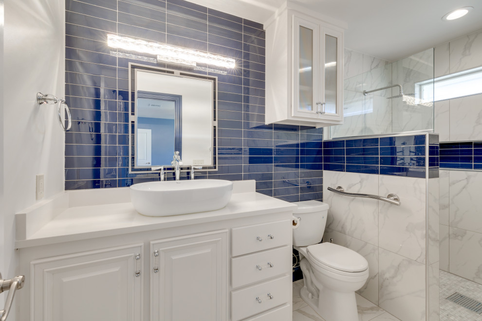 На фото: большая главная ванная комната в стиле неоклассика (современная классика) с фасадами с выступающей филенкой, синими фасадами, душем без бортиков, керамической плиткой, белыми стенами, полом из керамогранита, настольной раковиной, столешницей из гранита, разноцветным полом, белой столешницей, нишей, тумбой под две раковины, встроенной тумбой, синей плиткой и открытым душем