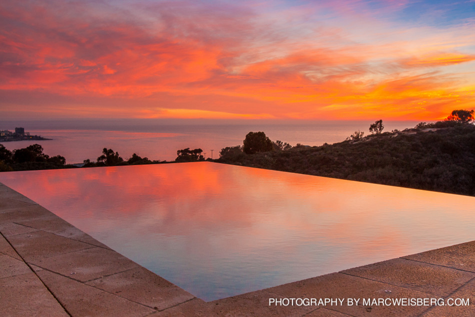 Mid-sized mediterranean backyard rectangular infinity pool in San Diego with natural stone pavers.