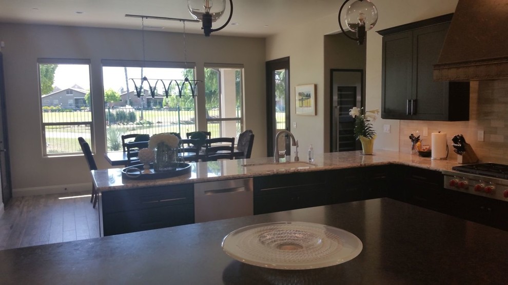 Open concept kitchen - large transitional u-shaped brown floor open concept kitchen idea with an undermount sink, recessed-panel cabinets, dark wood cabinets, granite countertops, beige backsplash, porcelain backsplash, stainless steel appliances and an island