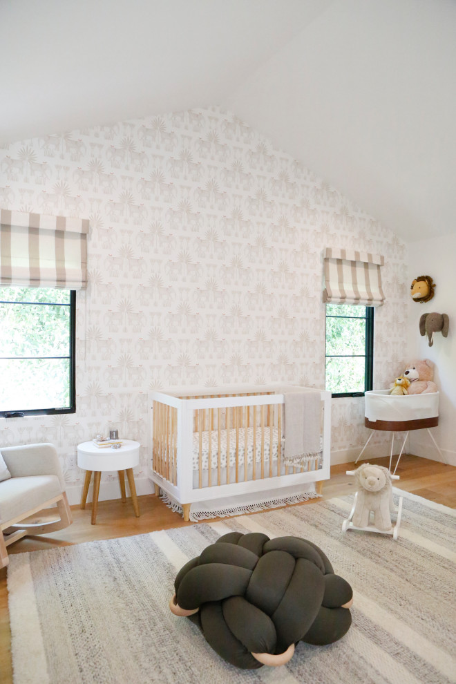 Ejemplo de habitación de bebé niña abovedada actual con paredes blancas, suelo de madera en tonos medios, suelo marrón y papel pintado