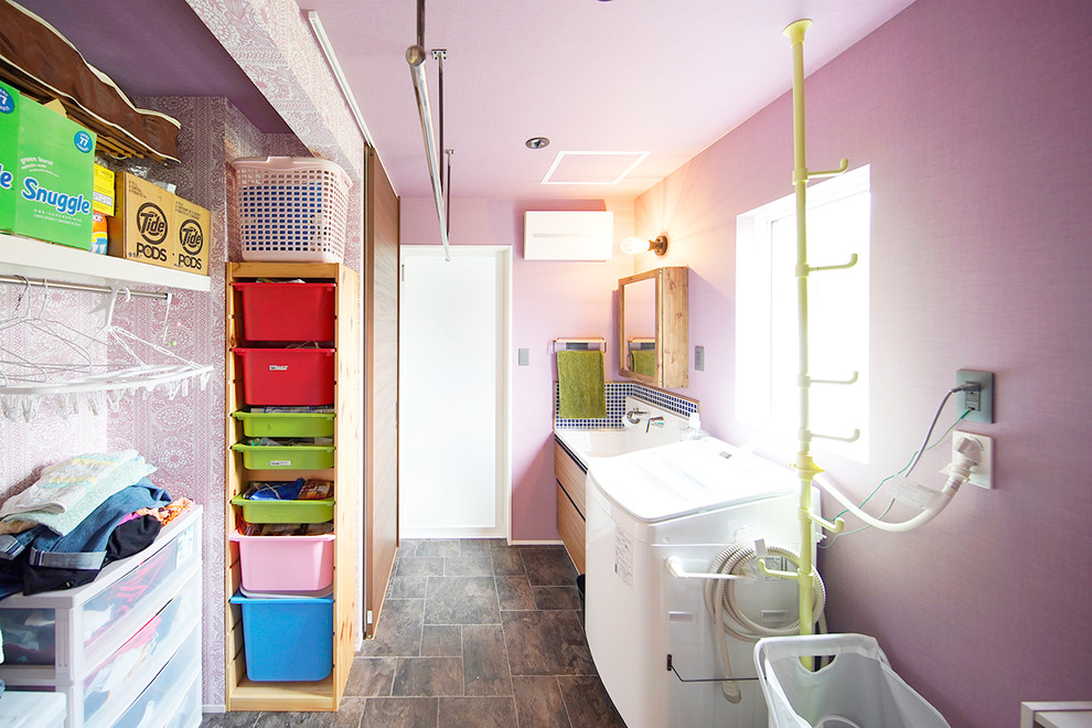This is an example of an industrial laundry room in Other with pink walls and brown floor.