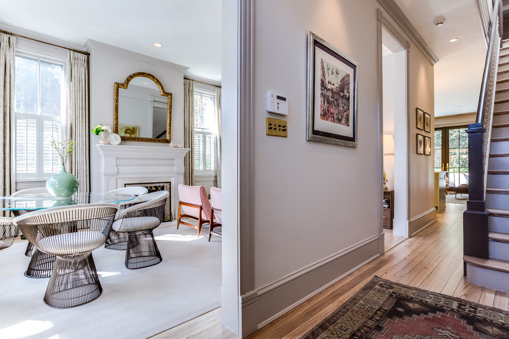Inspiration for a mid-sized transitional open plan dining in DC Metro with grey walls, light hardwood floors, a standard fireplace, a plaster fireplace surround and beige floor.