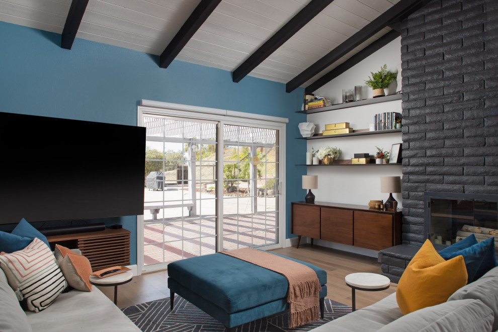 Mittelgroßes Maritimes Wohnzimmer mit weißer Wandfarbe, hellem Holzboden, Tunnelkamin, Kaminumrandung aus Backstein, TV-Wand, braunem Boden und freigelegten Dachbalken in San Diego
