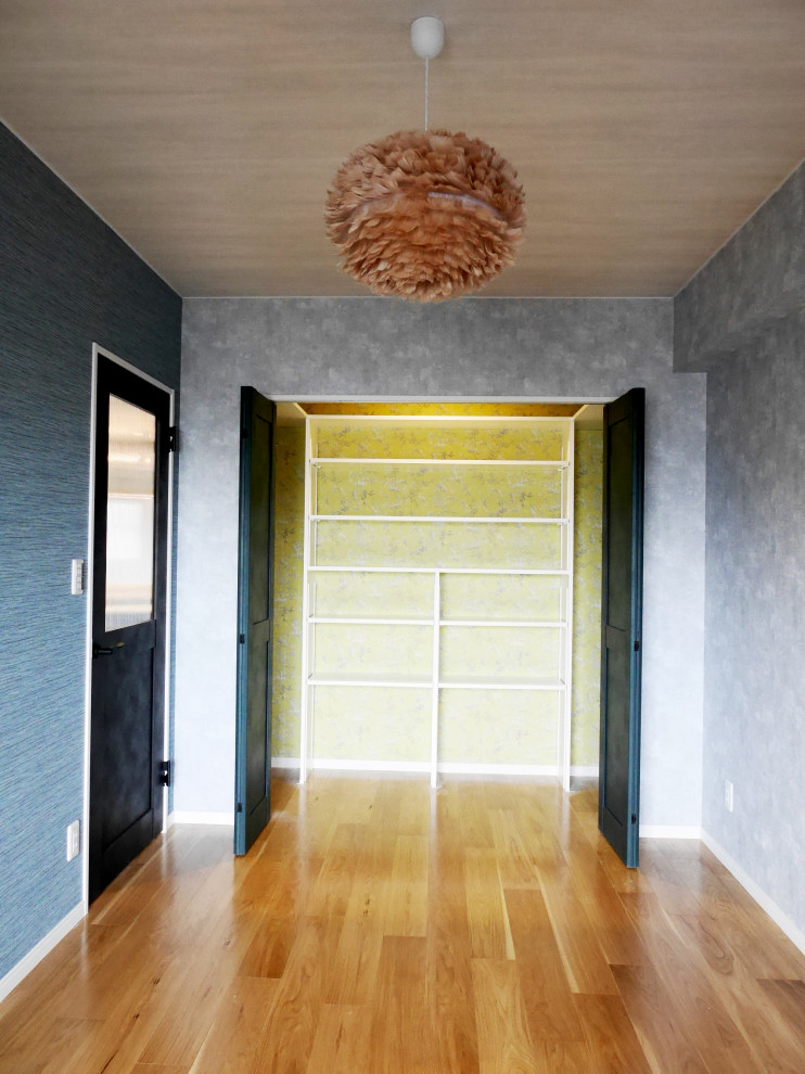 Foto de armario unisex actual pequeño con puertas de armario blancas, suelo de contrachapado, suelo marrón, armarios con paneles lisos y papel pintado