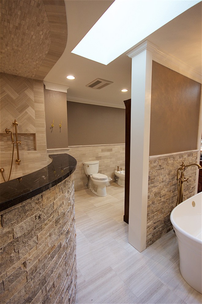 Photo of a large contemporary master bathroom in Austin with beaded inset cabinets, dark wood cabinets, a freestanding tub, an open shower, a bidet, beige tile, beige walls, ceramic floors, a drop-in sink and granite benchtops.