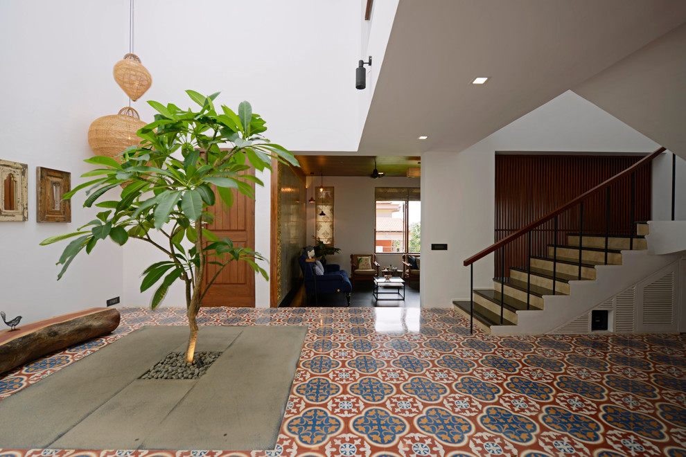 This is an example of a tropical foyer in Mumbai with white walls, ceramic floors and multi-coloured floor.