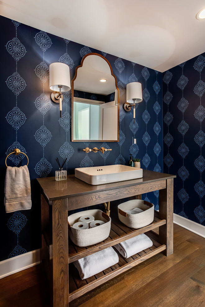 This is an example of a mid-sized country powder room in Los Angeles with furniture-like cabinets, dark wood cabinets, blue walls, medium hardwood floors, a vessel sink, brown floor, brown benchtops and wood benchtops.