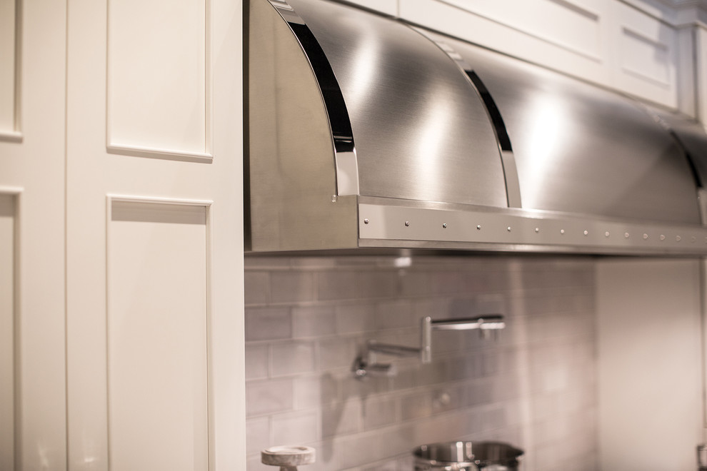 Example of a large transitional l-shaped dark wood floor, brown floor and vaulted ceiling eat-in kitchen design in Chicago with a farmhouse sink, white cabinets, quartzite countertops, white backsplash, subway tile backsplash, stainless steel appliances, gray walls, an island, recessed-panel cabinets and white countertops