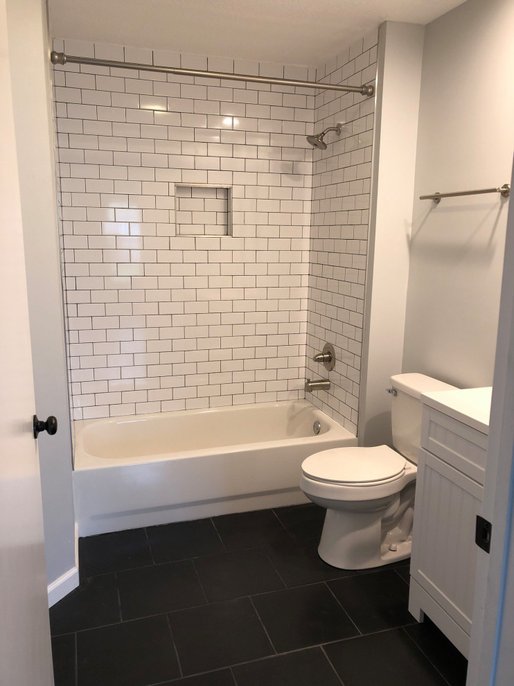 Photo of a small arts and crafts kids bathroom in San Diego with beaded inset cabinets, white cabinets, an alcove tub, a shower/bathtub combo, a two-piece toilet, white tile, ceramic tile, grey walls, porcelain floors, an undermount sink, marble benchtops, black floor, a shower curtain, white benchtops, a niche, a single vanity and a freestanding vanity.