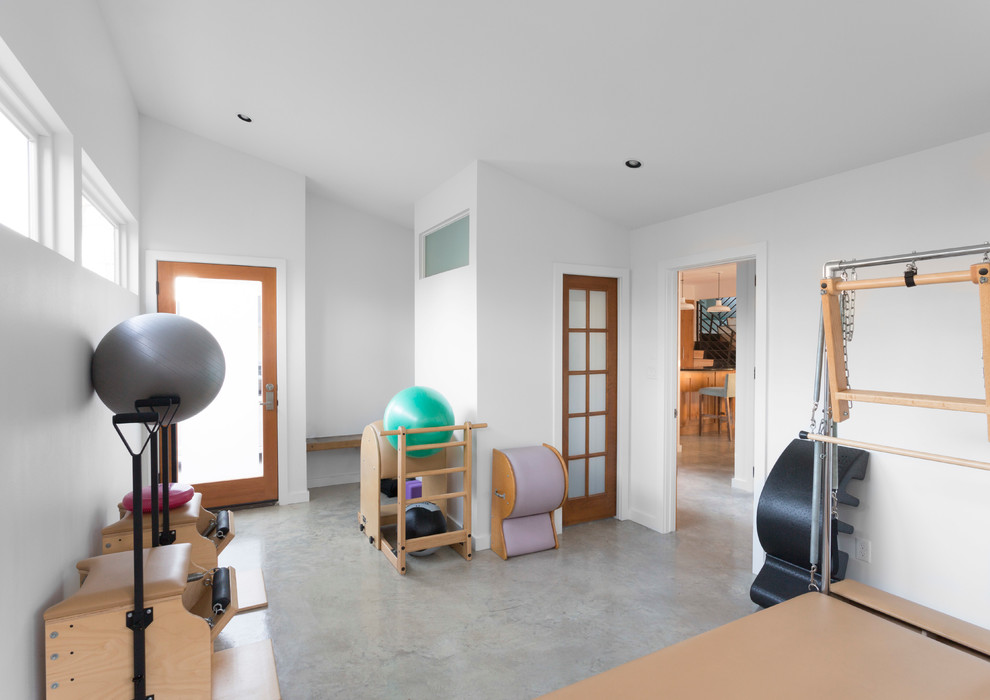 Photo of a contemporary home yoga studio in Austin with white walls and concrete floors.