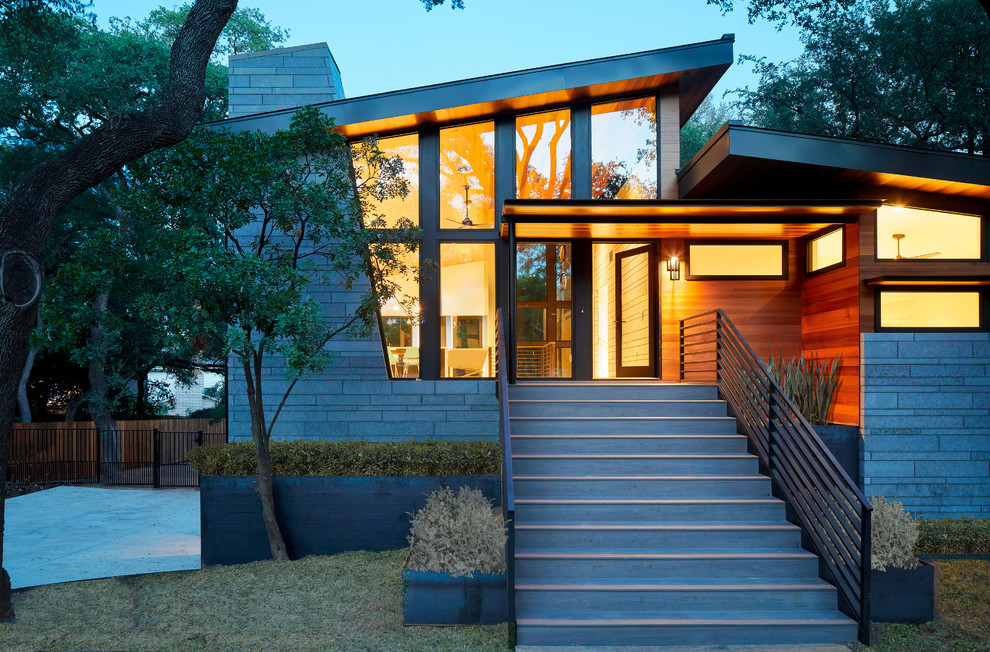 This is an example of a midcentury split-level house exterior in Austin with mixed siding and a metal roof.