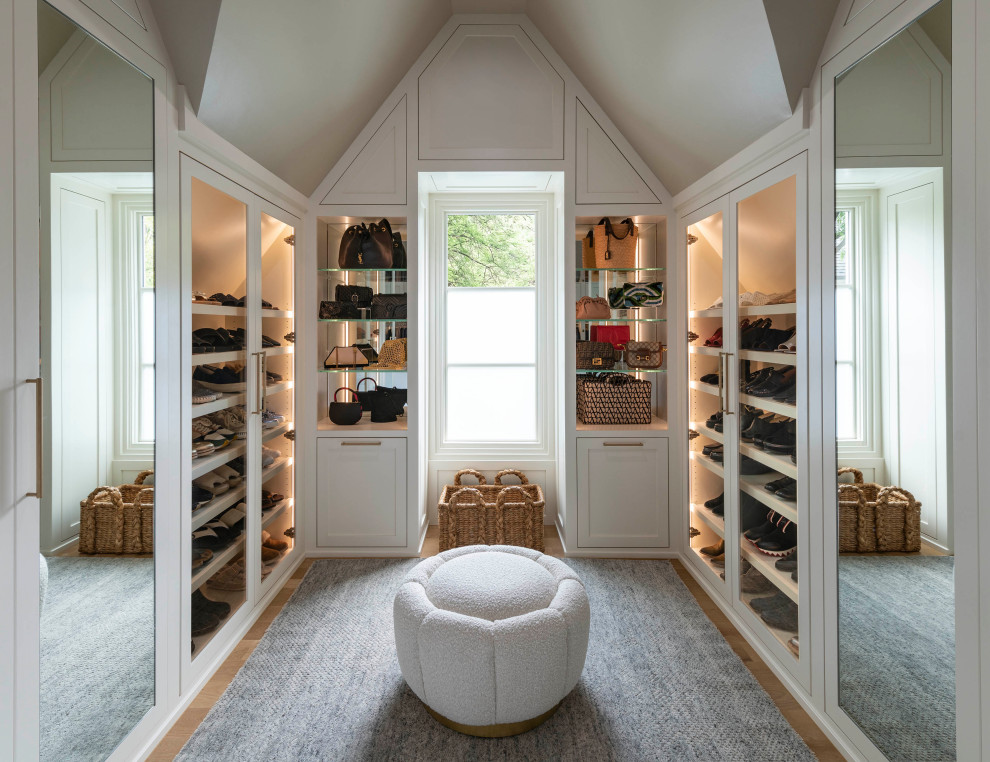 Photo of a large transitional gender-neutral walk-in wardrobe in Dallas with shaker cabinets, white cabinets, light hardwood floors, brown floor and vaulted.