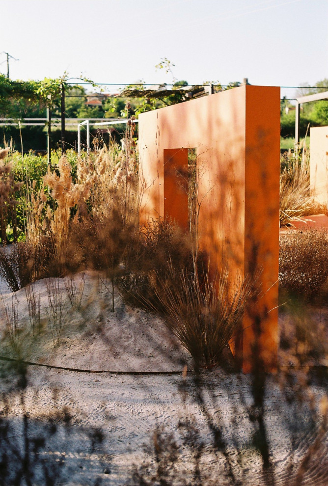 This is an example of a large and desert look modern courtyard partial sun xeriscape in Other with gravel.