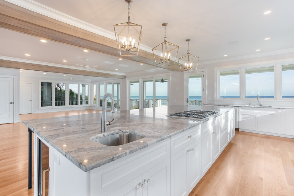 This is an example of a large contemporary l-shaped eat-in kitchen in Wilmington with an undermount sink, recessed-panel cabinets, white cabinets, quartzite benchtops, white splashback, timber splashback, black appliances, light hardwood floors, with island, blue benchtop and exposed beam.