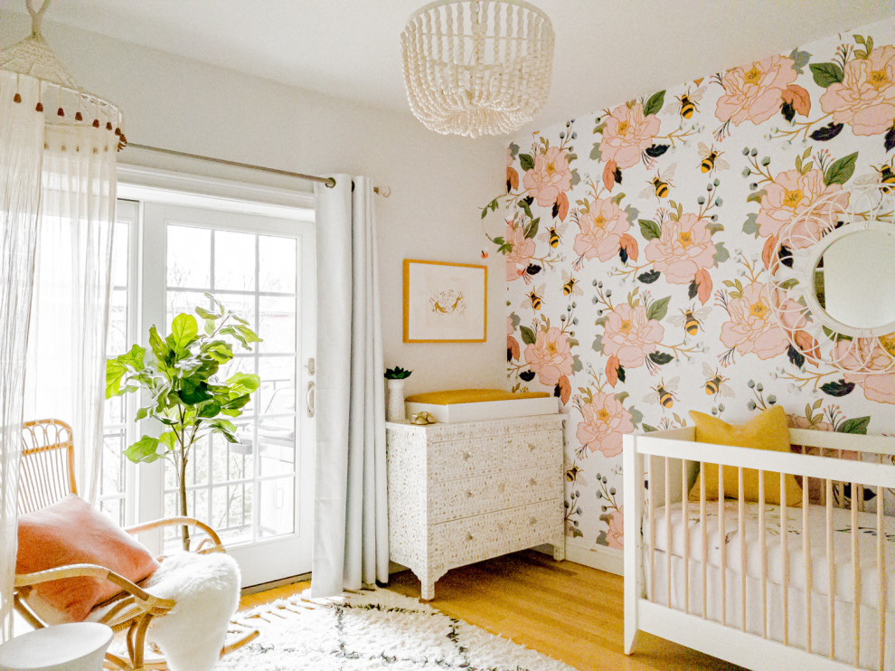 Mid-sized eclectic nursery in New York with multi-coloured walls, light hardwood floors, brown floor and wallpaper for girls.