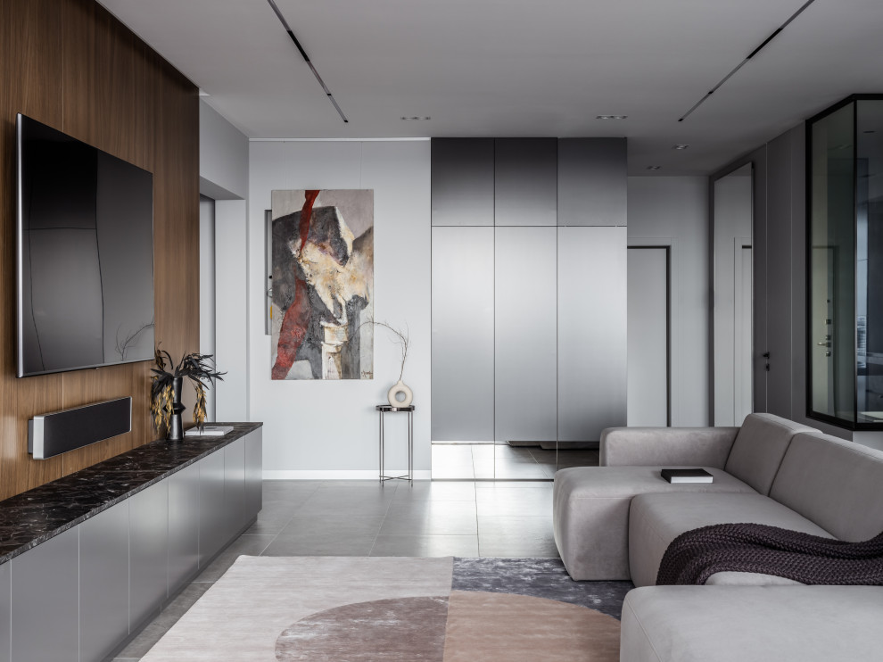 This is an example of a medium sized contemporary grey and white living room in Moscow with a home bar, grey walls, porcelain flooring, a ribbon fireplace, a stacked stone fireplace surround, a wall mounted tv, grey floors, a drop ceiling and wainscoting.