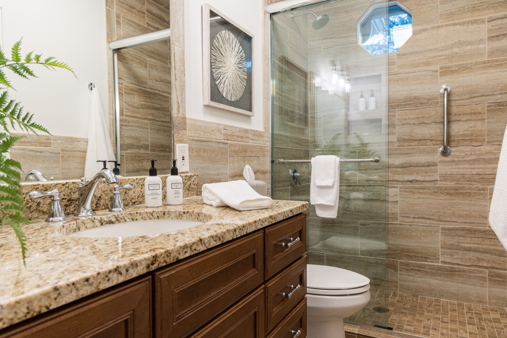 Inredning av ett klassiskt flerfärgad flerfärgat en-suite badrum, med bruna skåp, ett fristående badkar, en dusch/badkar-kombination, en toalettstol med separat cisternkåpa, beige kakel, keramikplattor, vita väggar, travertin golv, granitbänkskiva, vitt golv och dusch med skjutdörr