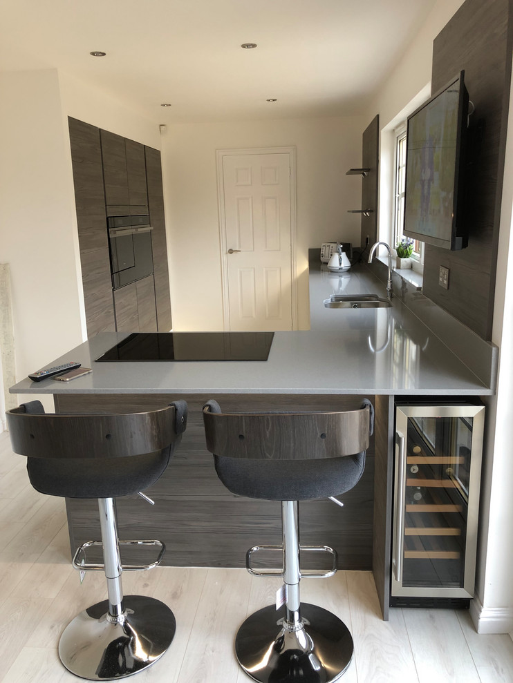 Design ideas for a mid-sized contemporary l-shaped eat-in kitchen in Glasgow with an integrated sink, flat-panel cabinets, grey cabinets, quartzite benchtops, brown splashback, timber splashback, stainless steel appliances, vinyl floors, a peninsula, grey floor and grey benchtop.
