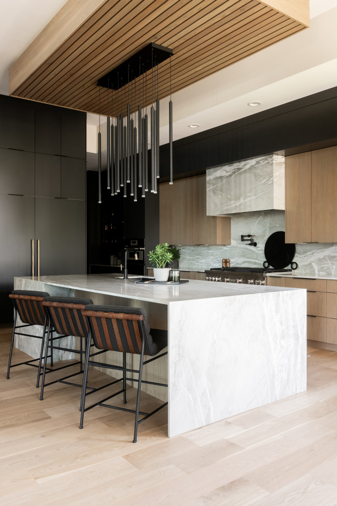 This is an example of a large modern kitchen pantry in Salt Lake City with an undermount sink, flat-panel cabinets, black cabinets, quartzite benchtops, panelled appliances, light hardwood floors, with island, brown floor and grey benchtop.