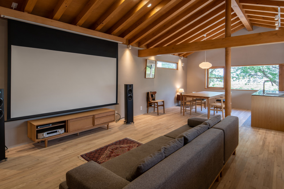 Design ideas for a scandinavian open concept home theatre in Other with grey walls, light hardwood floors, a projector screen and beige floor.