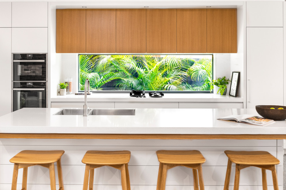 Design ideas for a medium sized contemporary galley kitchen/diner in Sydney with a double-bowl sink, flat-panel cabinets, white cabinets, engineered stone countertops, white splashback, an island and white worktops.