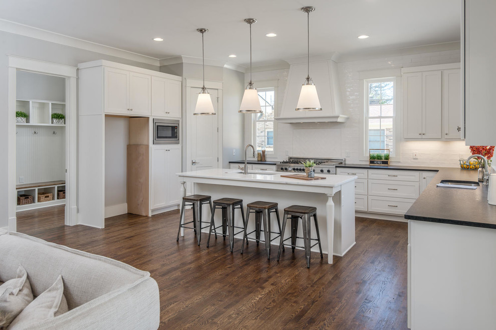 Design ideas for an expansive transitional kitchen in Nashville with a single-bowl sink, shaker cabinets, white cabinets, granite benchtops, white splashback, stainless steel appliances, dark hardwood floors, with island and brown floor.