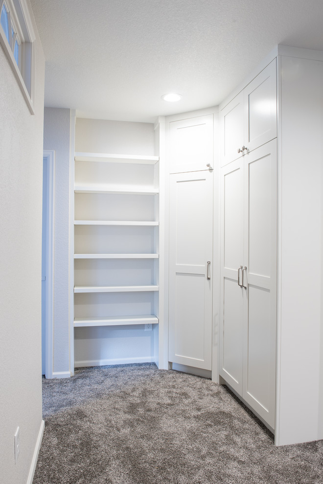 Photo of a mid-sized contemporary gender-neutral built-in wardrobe in Denver with shaker cabinets, white cabinets and carpet.