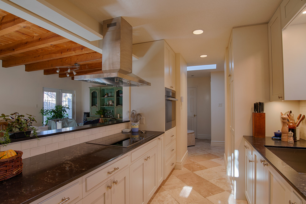 Small transitional galley limestone floor and beige floor open concept kitchen photo in Albuquerque with a peninsula, an undermount sink, shaker cabinets, white cabinets, solid surface countertops, white backsplash, subway tile backsplash and stainless steel appliances