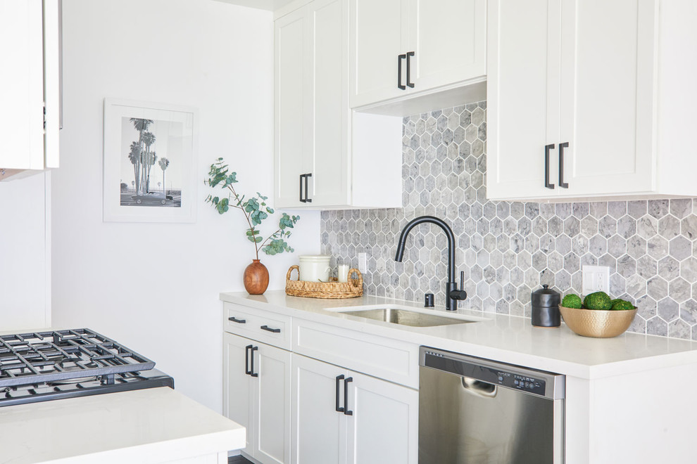 This is an example of a small transitional galley kitchen in Los Angeles with an undermount sink, shaker cabinets, white cabinets, grey splashback, stainless steel appliances and white benchtop.
