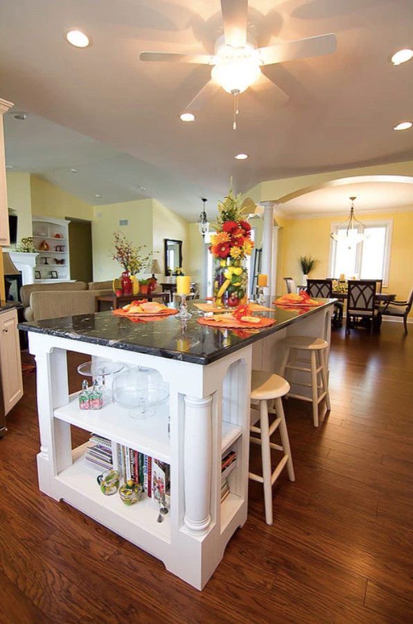 This is an example of a large transitional u-shaped eat-in kitchen in Other with an undermount sink, raised-panel cabinets, white cabinets, quartzite benchtops, white splashback, glass tile splashback, stainless steel appliances, medium hardwood floors, with island, brown floor and black benchtop.