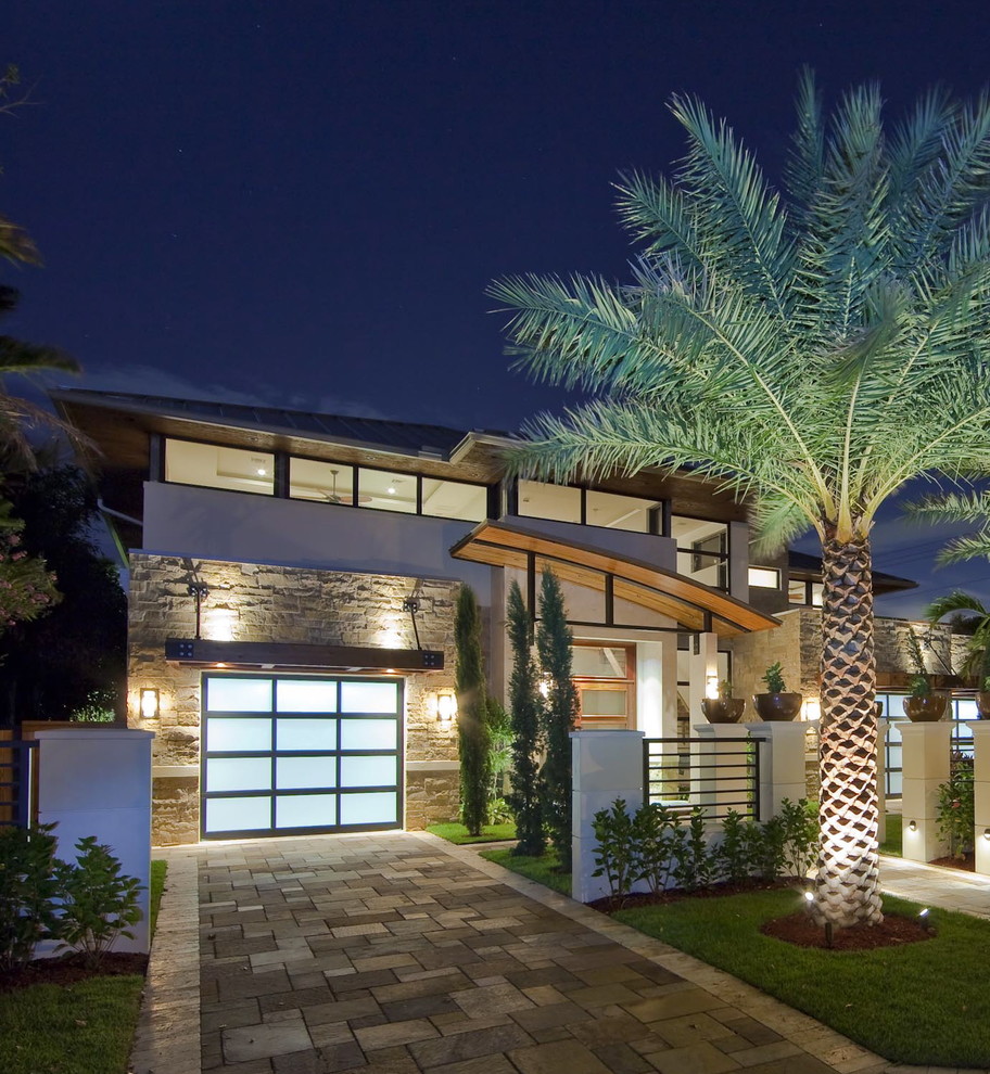This is an example of a mid-sized contemporary two-storey beige exterior in Miami with stone veneer.