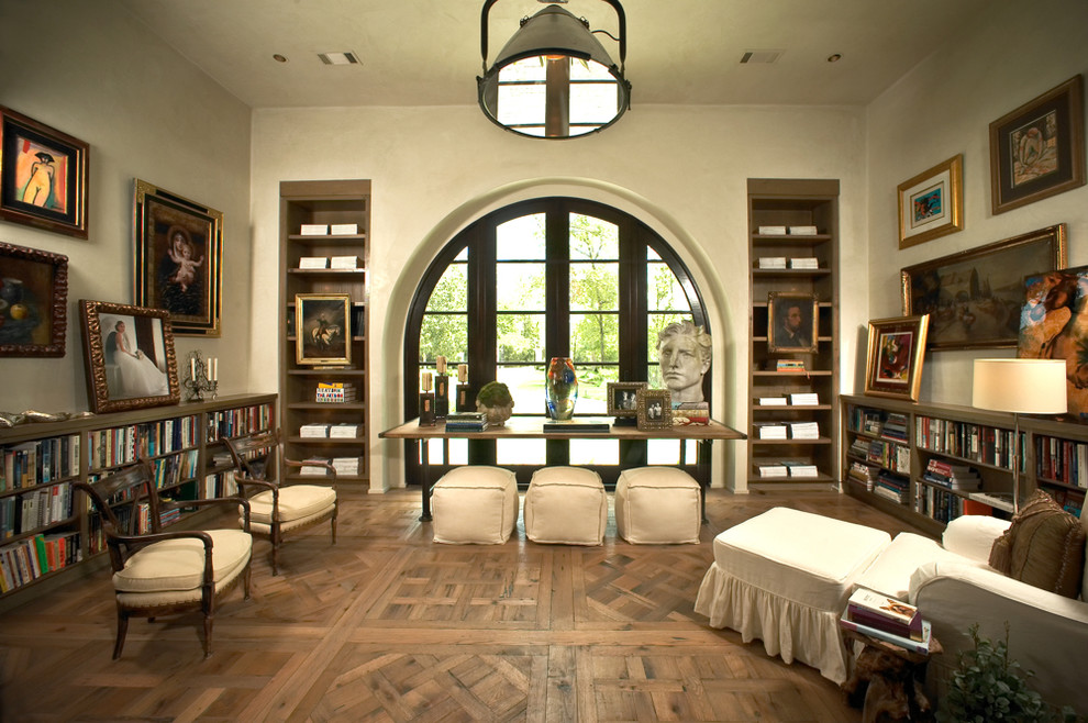 This is an example of a large country home office in Houston with a library, white walls, medium hardwood floors and a freestanding desk.