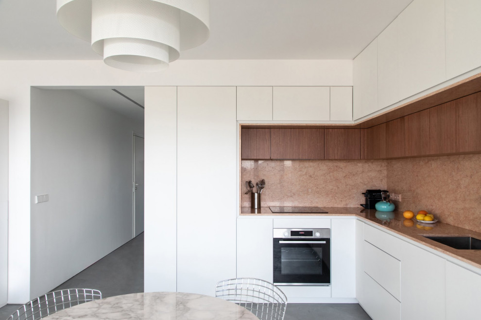 This is an example of a large contemporary l-shaped eat-in kitchen in Paris with an integrated sink, beaded inset cabinets, white cabinets, marble benchtops, pink splashback, marble splashback, panelled appliances, concrete floors, grey floor and pink benchtop.