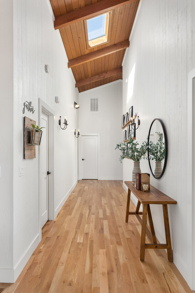 Small country hallway in Portland with white walls, light hardwood floors and beige floor.