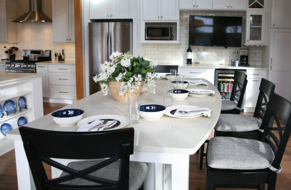 Exempel på ett stort maritimt vit vitt kök och matrum, med en undermonterad diskho, skåp i shakerstil, vita skåp, bänkskiva i kvarts, vitt stänkskydd, stänkskydd i porslinskakel, rostfria vitvaror, ljust trägolv, flera köksöar och brunt golv