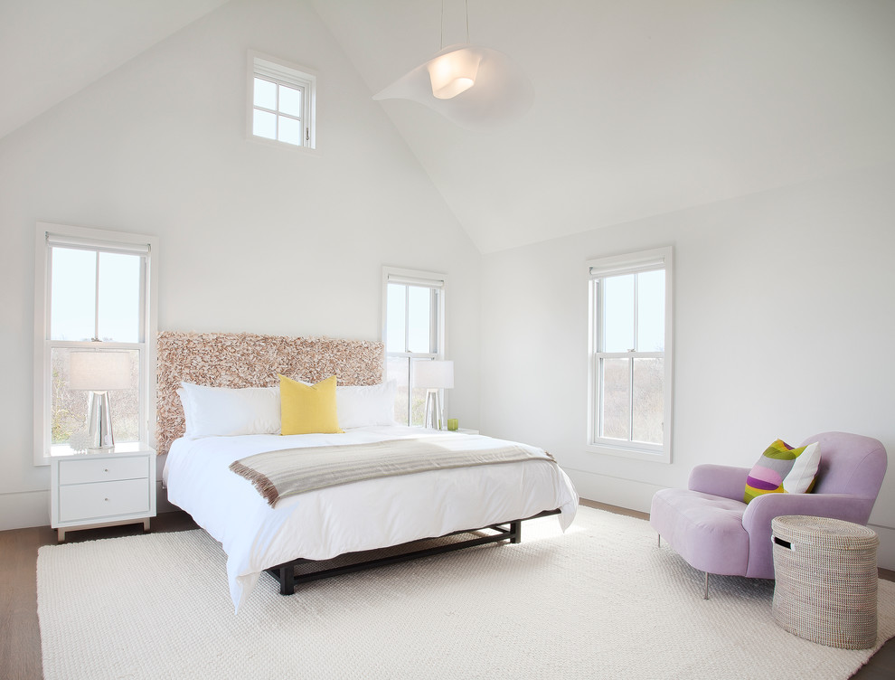 Photo of a large beach style bedroom in Boston with white walls and medium hardwood floors.