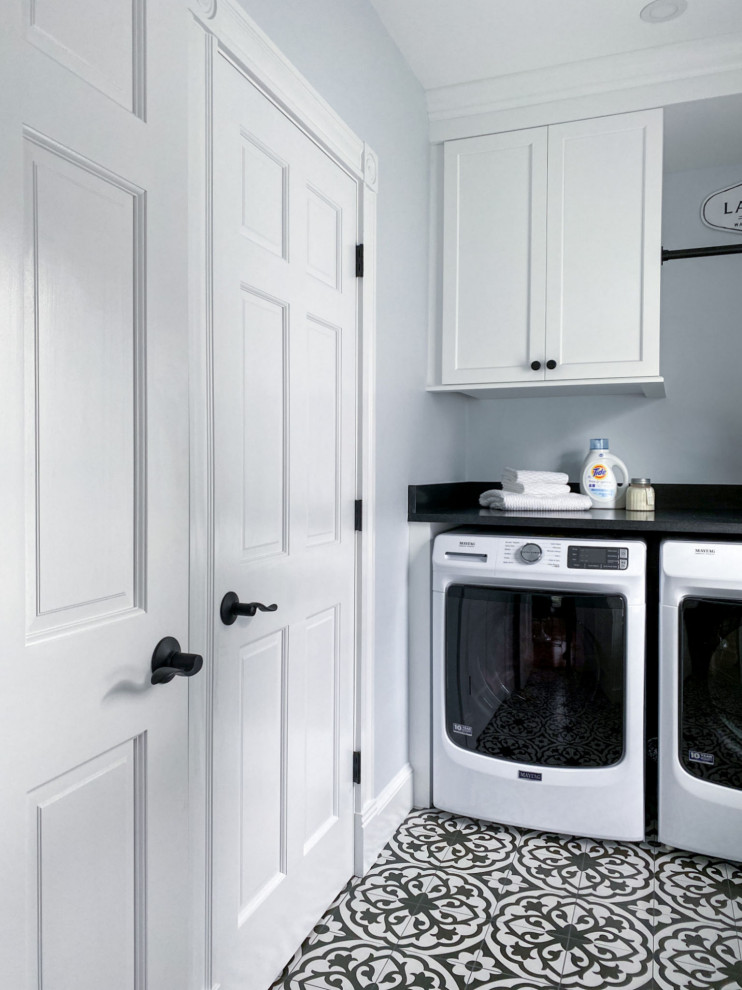 Klassische Waschküche mit Schrankfronten im Shaker-Stil, weißen Schränken, Granit-Arbeitsplatte, blauer Wandfarbe, Porzellan-Bodenfliesen, Waschmaschine und Trockner nebeneinander, schwarzem Boden und schwarzer Arbeitsplatte in Boston