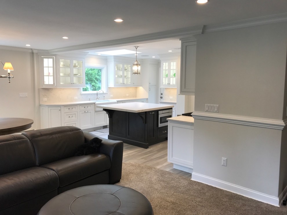 Inspiration for a mid-sized transitional u-shaped light wood floor and brown floor open concept kitchen remodel with a farmhouse sink, recessed-panel cabinets, white cabinets, marble countertops, white backsplash, marble backsplash, stainless steel appliances and an island