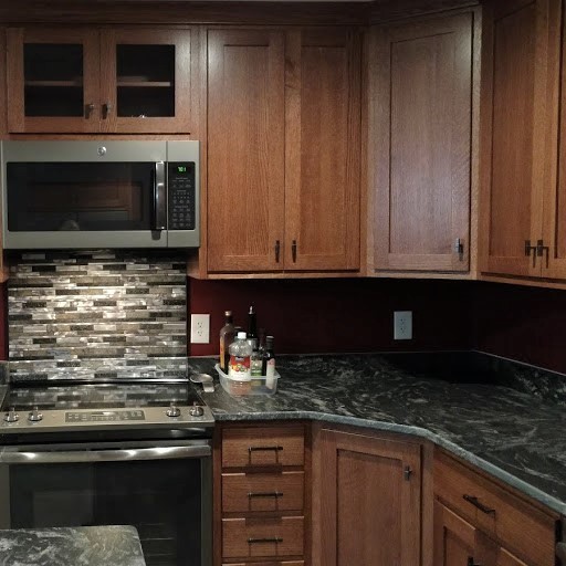 Home design - large transitional u-shaped home design idea with recessed-panel cabinets, medium tone wood cabinets, granite countertops, multicolored backsplash, stainless steel appliances, an island and multicolored countertops