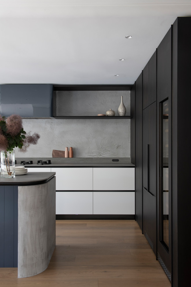 Inspiration for a large contemporary l-shaped open plan kitchen in Sydney with a double-bowl sink, flat-panel cabinets, concrete benchtops, grey splashback, porcelain splashback, black appliances, medium hardwood floors, with island and grey benchtop.