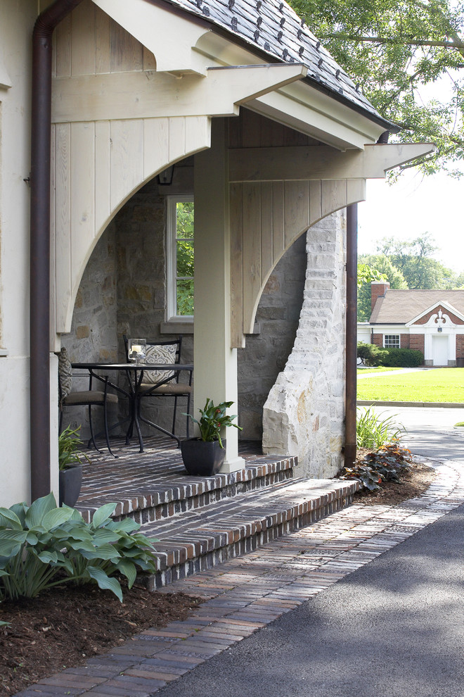 This is an example of a traditional verandah in Chicago with brick pavers and a roof extension.