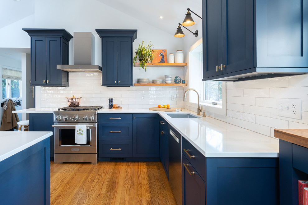 Photo of a classic l-shaped kitchen/diner in Philadelphia with a single-bowl sink, shaker cabinets, blue cabinets, quartz worktops, white splashback, metro tiled splashback, stainless steel appliances, medium hardwood flooring, brown floors, white worktops and a vaulted ceiling.