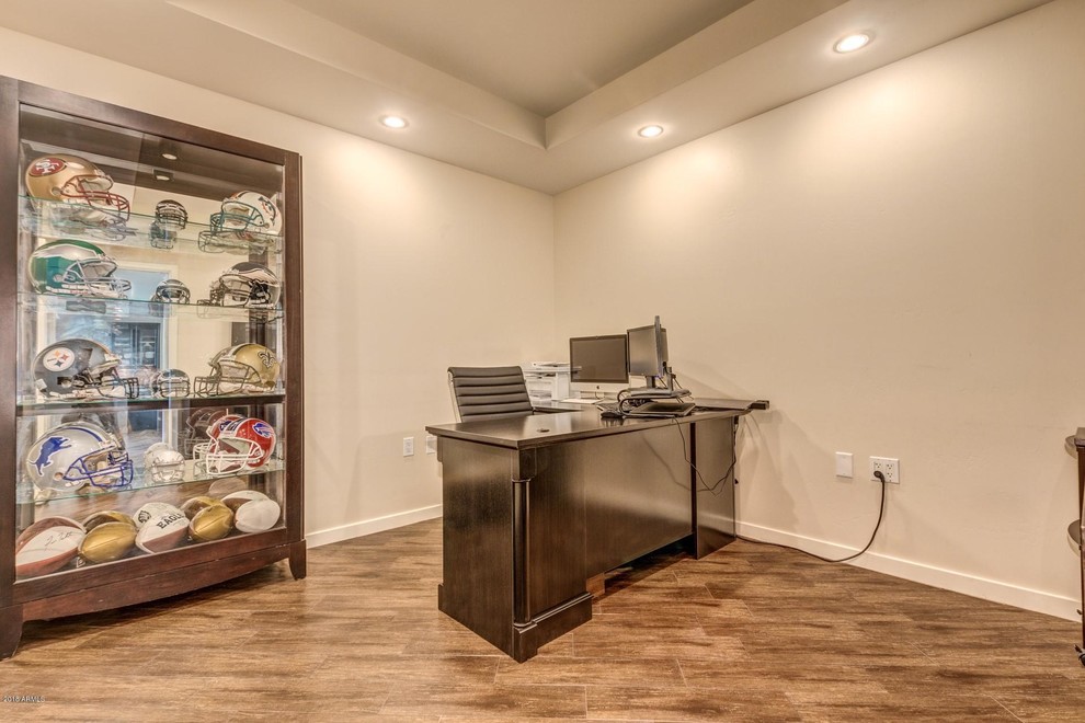 This is an example of a large transitional home office in Phoenix with beige walls, a freestanding desk and brown floor.