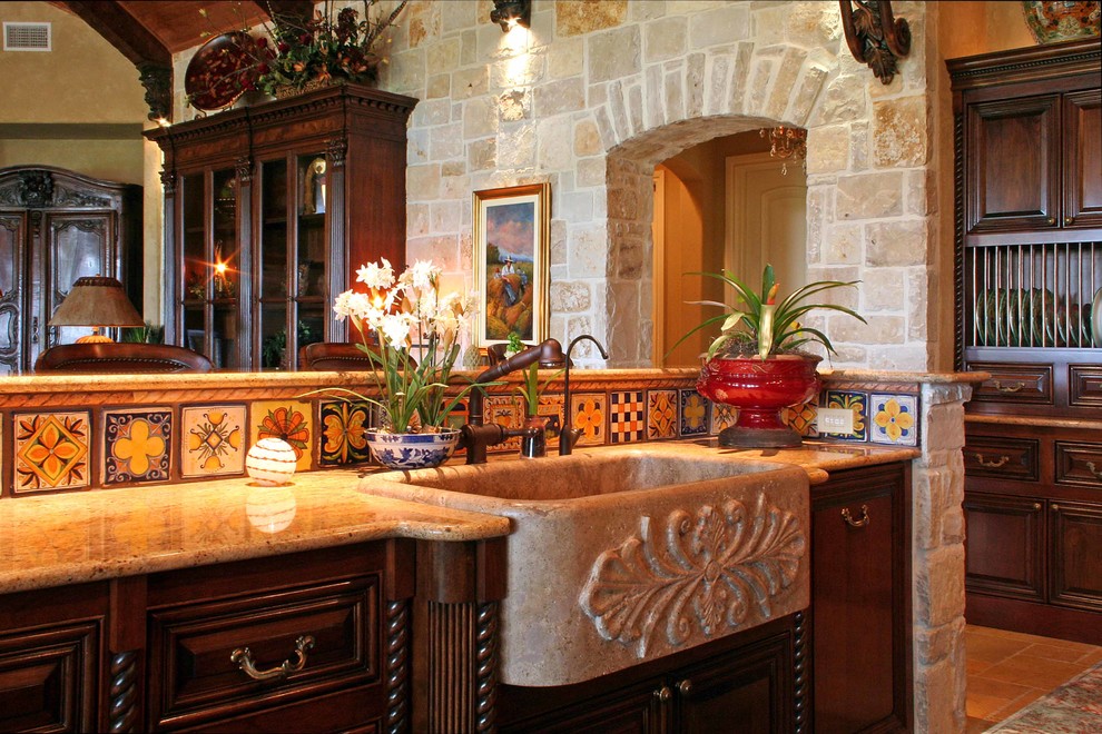 Photo of a large mediterranean galley open plan kitchen in Austin with a farmhouse sink, beaded inset cabinets, dark wood cabinets, granite benchtops, multi-coloured splashback, ceramic splashback, travertine floors and multiple islands.