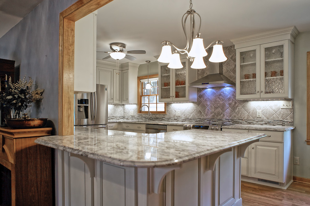 Example of a large transitional u-shaped medium tone wood floor eat-in kitchen design with raised-panel cabinets, white cabinets, granite countertops, gray backsplash, stainless steel appliances, yellow walls, a peninsula, a single-bowl sink and ceramic backsplash