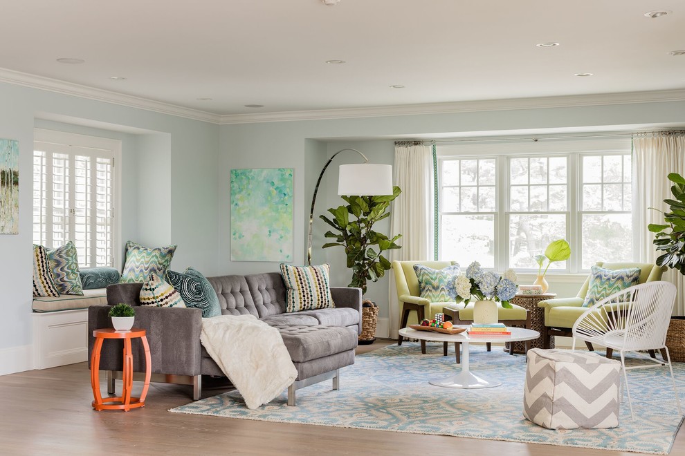 This is an example of a beach style family room in Boston with blue walls, light hardwood floors and brown floor.