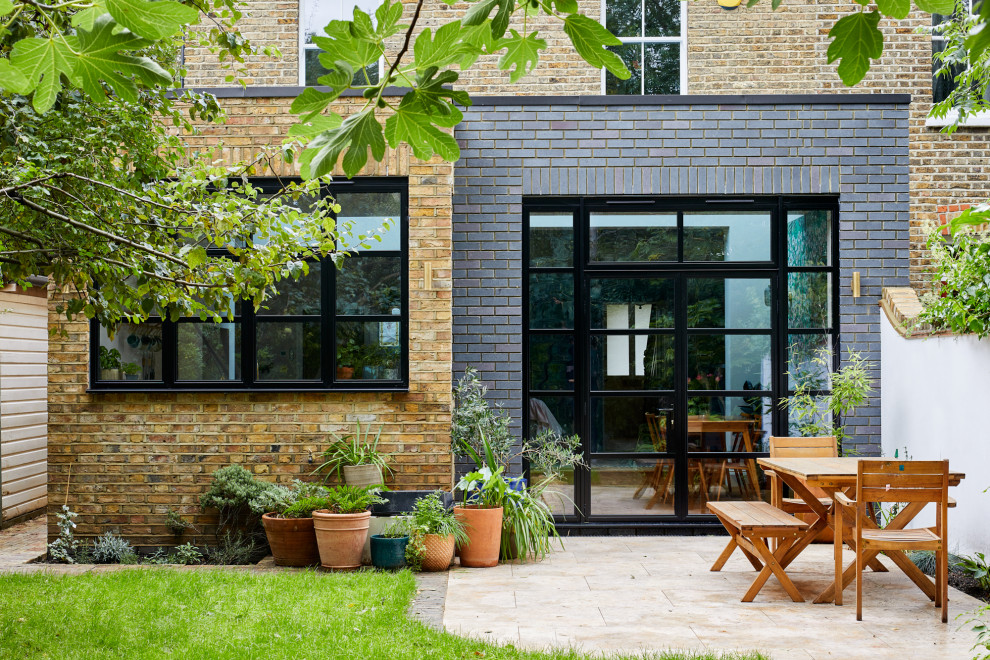 Inspiration for a mid-sized transitional three-story brick flat roof remodel in London with a mixed material roof
