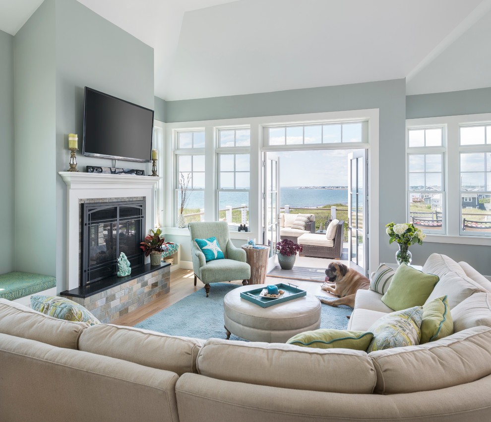 This is an example of a mid-sized beach style open concept living room in Providence with blue walls, light hardwood floors, a standard fireplace, a wood fireplace surround and a wall-mounted tv.